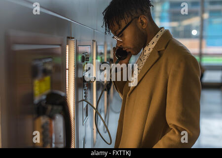 Serious young businessman talking on train station pay phone Stock Photo