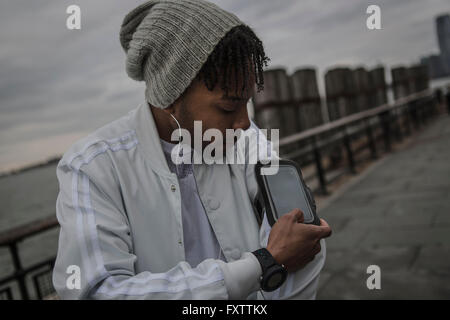 Young man training on riverside at dawn using smartphone touchscreen Stock Photo