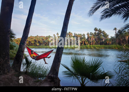 Man relaxing in hammock by lake, Baja California, Mexico Stock Photo