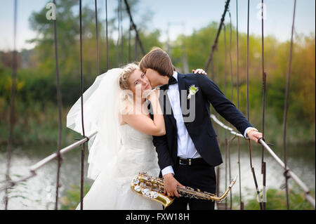 happy groom kisses bride on bridge in their wedding day Stock Photo