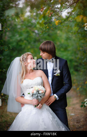 Elegant young happy wedding couple is sitting at green grass on green ...