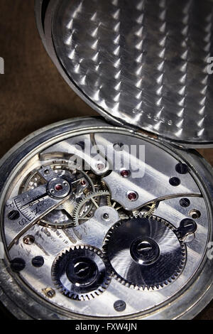 Pocket watch inside on wooden desk with wheels and springs silver color Stock Photo