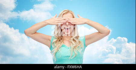 smiling young woman or teen girl covering her eyes Stock Photo