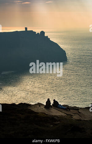Two people lie on the Cliffs of Moher and watch the evening light over Hag's Head Stock Photo