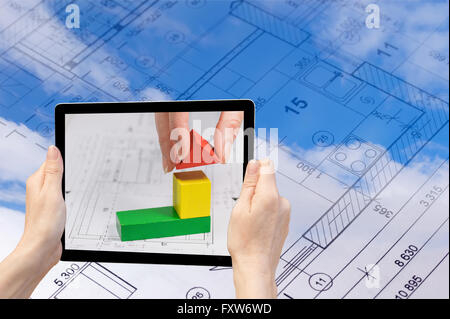 In the bottom left of the photo are hands holding tablet, whose screen contains photo of construction abstract Stock Photo