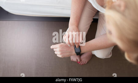 Top view shot of a woman using smart watch. She is dialing a phone number for a phone call. Focus on smart watch and hands. Stock Photo