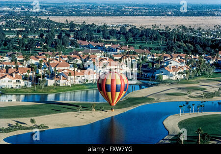 Sightseeing passengers in a hot air balloon float past a Palm Desert housing development in the sprawling Coachella Valley in Southern California, USA. This desert area is a retirement haven for senior citizens and vacant land has long been filling up with new homes to accommodate them. Stock Photo