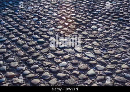 Cobbled stone road low angle, reflection of light seen on the road Stock Photo