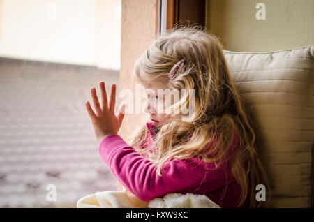 beautiful blond girl looking through window Stock Photo