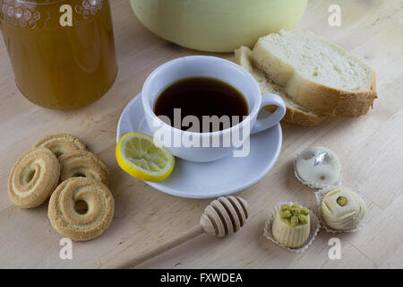 A cup on English tea, with honey on the background and small sweets as dessert for relaxing tea time moment Stock Photo