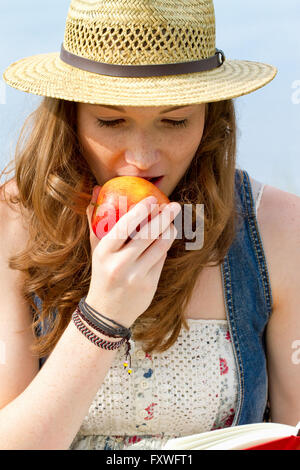 Young woman eating a apple and reading a book Stock Photo