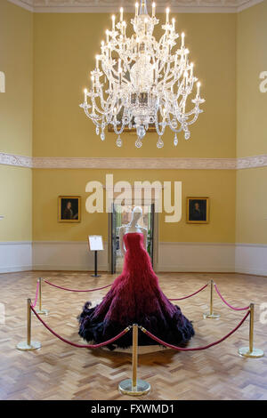 Bath, UK, 18th April, 2016. The GREAT dress a couture dress designed by Nicholas Oakwell and made especially for the government's GREAT campaign is pictured being unveiled by the curator of the Fashion Museum Rosemary Harden in the Octagon at the Assembly Rooms as the centre piece of the 2016 Bath in Fashion week. This one-of-a-kind dress was hand embellished with rubies and 200 000 ostrich feathers sewn in place by the Royal School of Needlework. Credit:  lynchpics/Alamy Live News Stock Photo