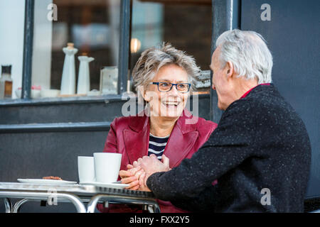 Romantic senior couple holding hands at sidewalk cafe Stock Photo