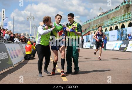 A paramedic and official helps a exhausted runner reach the finish line of the 2016 Brighton Marathon. Stock Photo