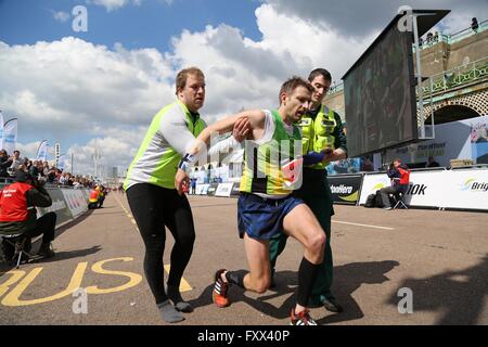 A paramedic and official helps a exhausted runner reach the finish line of the 2016 Brighton Marathon. Stock Photo