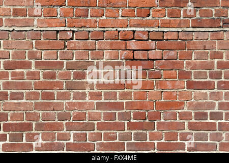 Background of old red brick wall with scratches, holes and gaps Stock Photo