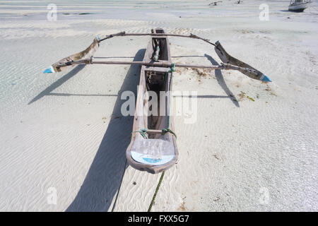 Dhow wooden boat lying dry at low tide on a beach at the Indian Ocean near Zanzibar, Tanzania Stock Photo