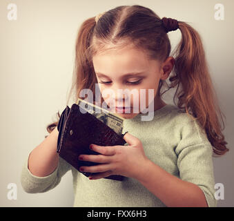 Cute surprising small kid girl looking in mother wallet and want to take money. Toned closeup portrait Stock Photo
