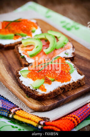 Delicious red caviar, avocado, salmon and cream cheese sandwiches Stock Photo