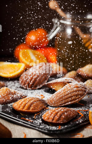 Homemade orange honey madeleines cookies and sugar powder motion Stock Photo