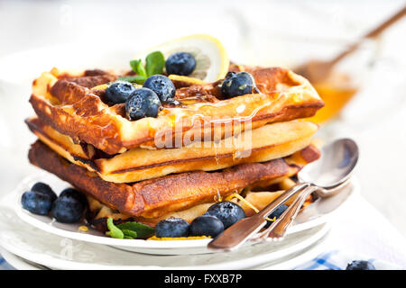 Lemon blueberry waffles with honey, zest, fresh berries and cup of tea Stock Photo