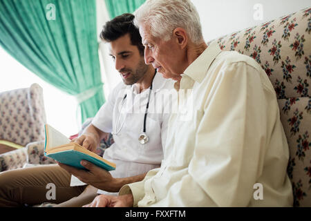 Nurse and senior man reading a book Stock Photo