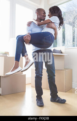 Young man lifting woman in his arms Stock Photo