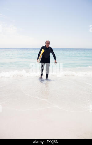 Senior man in wetsuit holding a surfboard Stock Photo