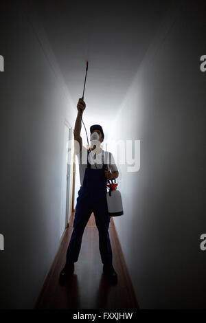 Front view of manual worker spraying on ceiling Stock Photo