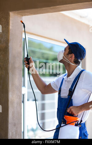 Side view of worker using pesticide on wall Stock Photo