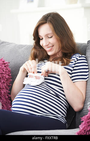 Pregnant Woman Holding Baby Shoes Stock Photo