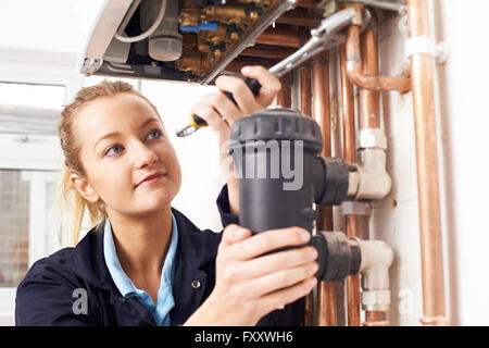 Female Plumber Working On Central Heating Boiler Stock Photo