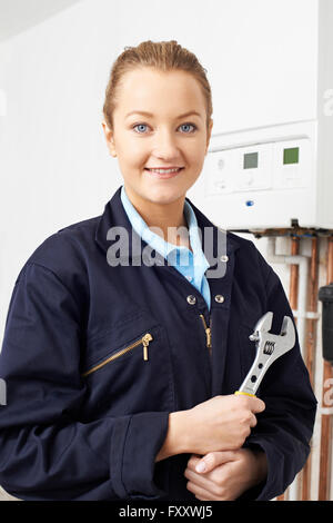 Female Plumber Working On Central Heating Boiler Stock Photo