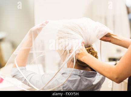 Stylist pinning up a bride's hairstyle and bridal veil before the wedding Stock Photo