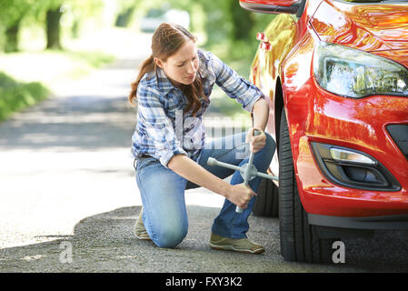Frustrated Female Driver With Tyre Iron Trying To Change Wheel Stock Photo
