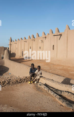 Two kids posing in front of the Great Mosque of Djenné, (Mali, Africa) an adobe building of Sudanese architecture Stock Photo