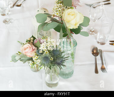 Table set for wedding or event with informal flower arrangements in vintage bottles Stock Photo