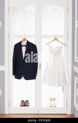 Tuxedo and wedding dress with shoes hung up on the windows Stock Photo