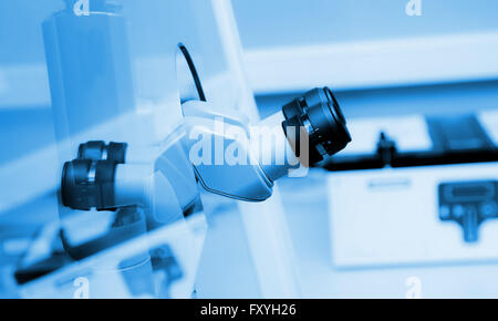 binocular microscope behind a sefety glass in a laboratory, grinish collored photo. Stock Photo