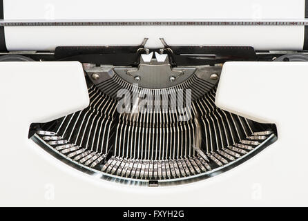 Detail view of an old fashioned typewriter from the 1970s with blank paper and moving hammer heads Detail view of an old fashioned typewriter from the 1970s with blank paper and moving hammer heads