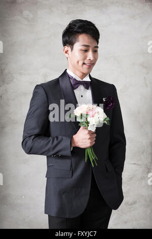 Bridegroom holding a bouquet and looking down with a smile Stock Photo