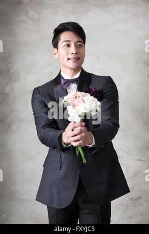 Bridegroom holding a bouquet and giving it forward with a smile Stock Photo