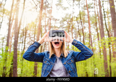 Woman wearing virtual reality goggles outside in spring nature Stock Photo