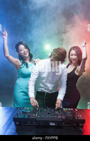 Two young smiling women dancing with DJ at nightclub Stock Photo