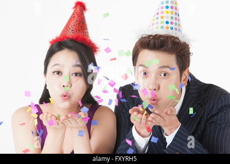 Portrait of young woman and a young man blowing confetti Stock Photo