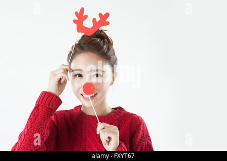 Portrait of young smiling woman putting on horns and nose of deer staring at front Stock Photo