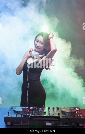 Young smiling female DJ posing staring at front at nightclub Stock Photo