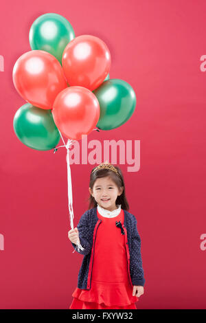 Smiling girl holding balloons staring at front Stock Photo