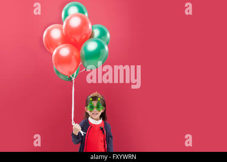 Portrait of smiling girl wearing a mask holding balloons staring at front Stock Photo