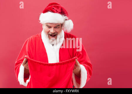 Portrait of surprised Santa holding and looking in a bag Stock Photo